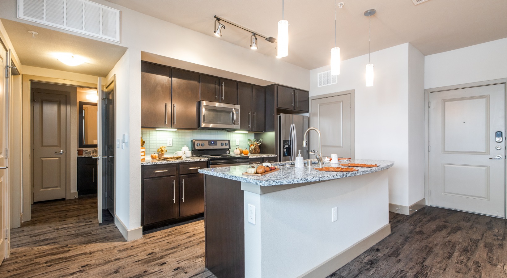 a kitchen with stainless steel appliances and hardwood floors at The  Carson @ Twin Creeks